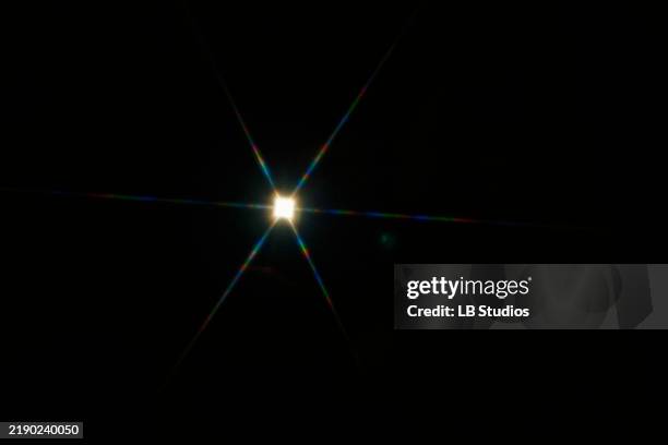 bright starburst light effect with colorful diffraction streaks on a black background - reflejo fotografías e imágenes de stock
