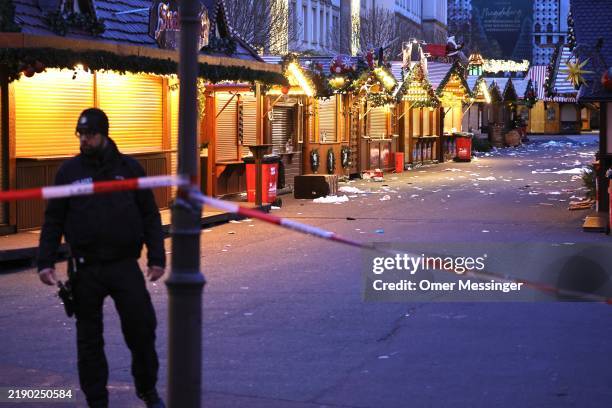Policeman walks through the shuttered Christmas market the day after a terror attack that has left five people dead, including a small child, and...