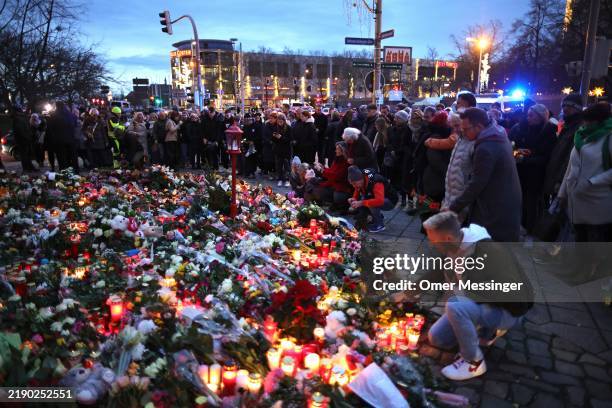 People lay flowers at a makeshift memorial near the shuttered Christmas market the day after a terror attack that has left five people dead,...
