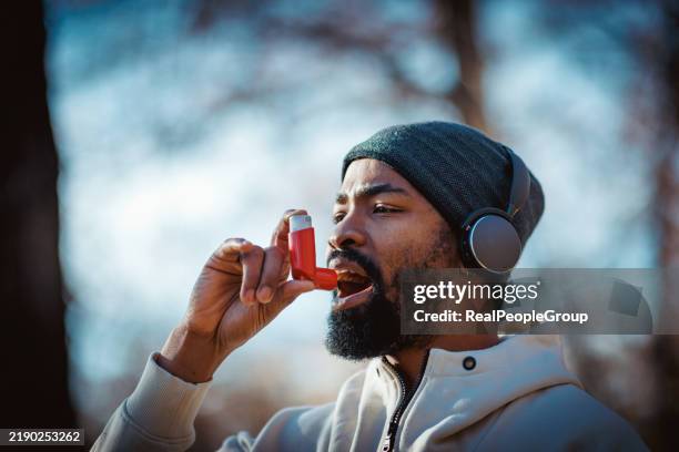 hombre adulto joven que usa inhalador mientras hace ejercicio al aire libre - inhalador-preventivo-del-asma fotografías e imágenes de stock