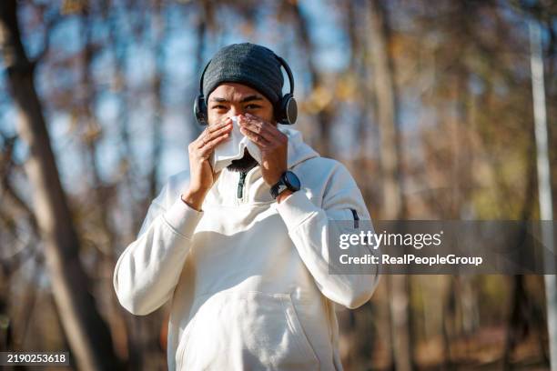 young man blowing his nose while exercising outdoors in autumn - snyta sig bildbanksfoton och bilder