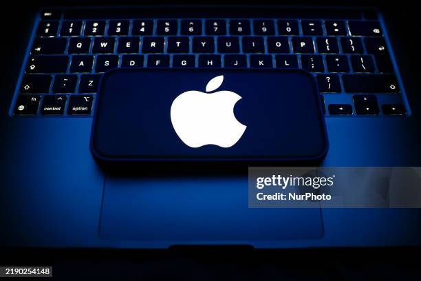 Laptop keyboard and Apple logo displayed on a smartphone are seen in this illustration photo taken in Krakow, Poland on December 21, 2024.