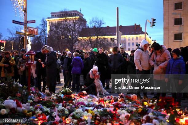 Woman embraces her dog as people lay flowers at a makeshift memorial near the shuttered Christmas market the day after a terror attack that has left...