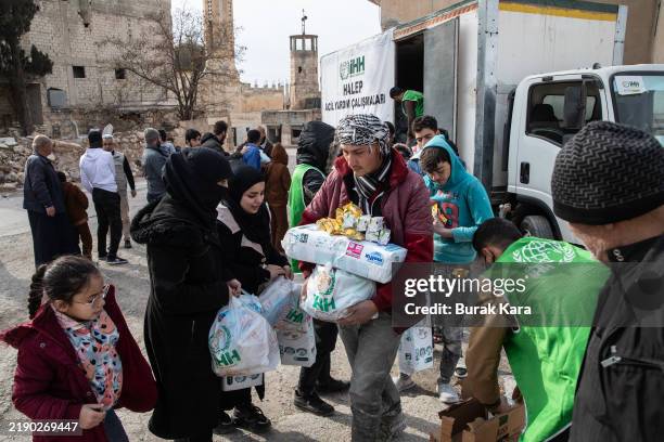 Syrians receive aid supplied by Humanitarian Relief Foundation's in el-Cedide district on December 16, 2024 in Aleppo, Syria. Aleppo was the first...