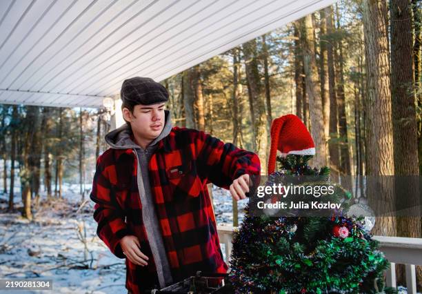 holiday decorating on snowy porch. autistic teen helps with christmas tree setup in winter forest setting - buffalo check stock pictures, royalty-free photos & images