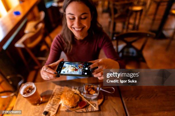 jeune femme prenant une photo de nourriture dans un restaurant avec un smartphone - gastronome photos et images de collection