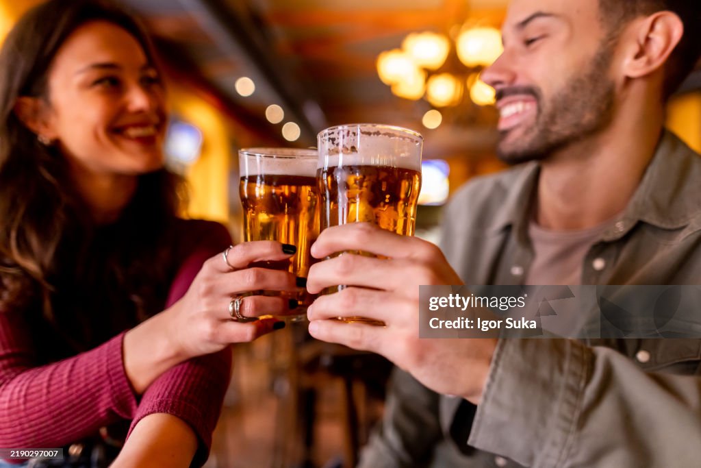 Happy couple toasting with beer glasses in a pub