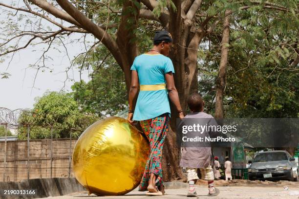 Woman walks back home with her son and a massive balloon after leaving the Catholic Church of Assumption Asokoro, hours after 10 people are crushed...