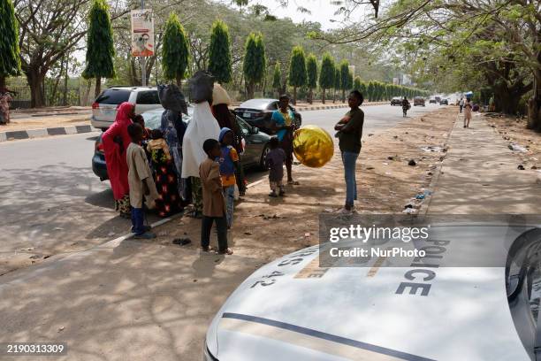People stand in front of a police truck, waiting to receive Christmas food palliatives, hours after 10 people are crushed during a stampede at the...