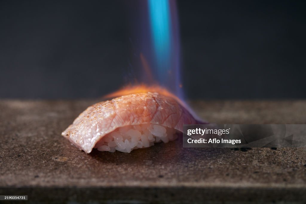 Piece of sushi being cooked on a stone