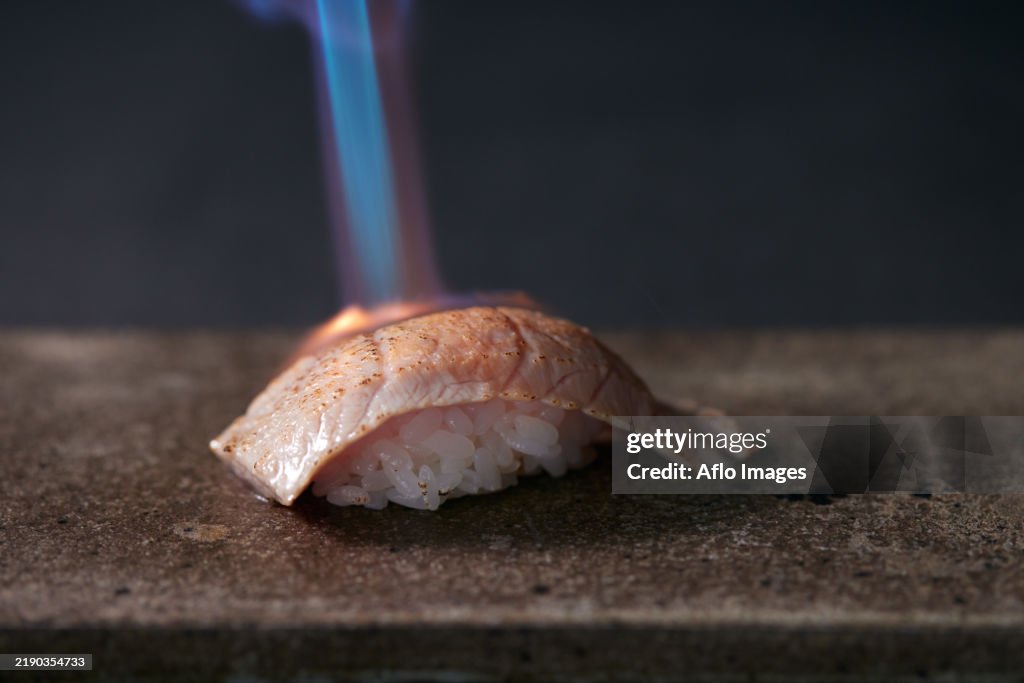 Piece of sushi being cooked on a stone