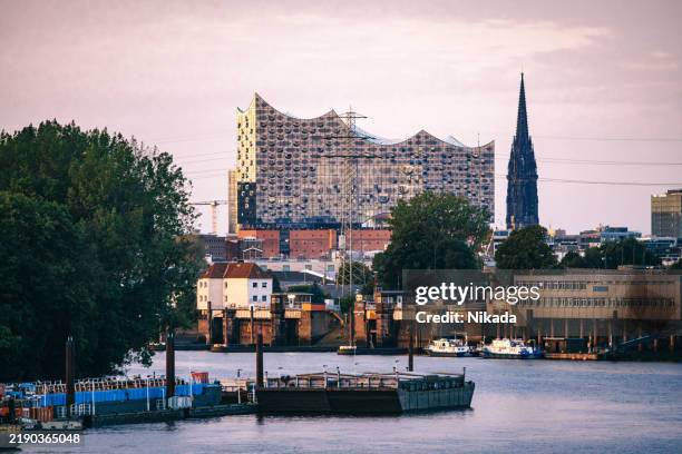 view on the elbe river towards elbphilharmonie at sunset - elbphilharmonie stock pictures, royalty-free photos & images