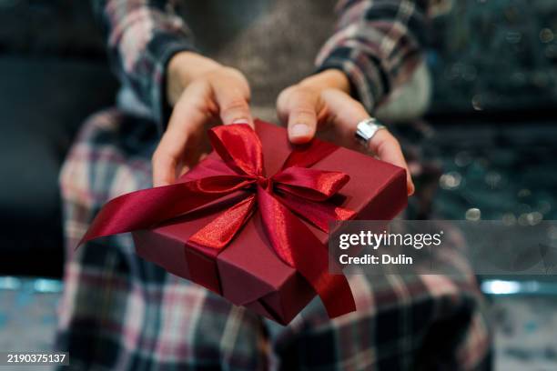 close-up of a woman holding a wrapped gift box with a satin ribbon - gift lounge stock-fotos und bilder