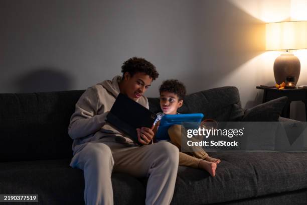 brothers using digital tablets on the sofa - sunderland stock pictures, royalty-free photos & images