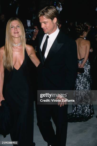 American actress Jennifer Aniston, wearing a black evening gown, and her partner, American actor Brad Pitt, wearing a black suit over a white shirt...
