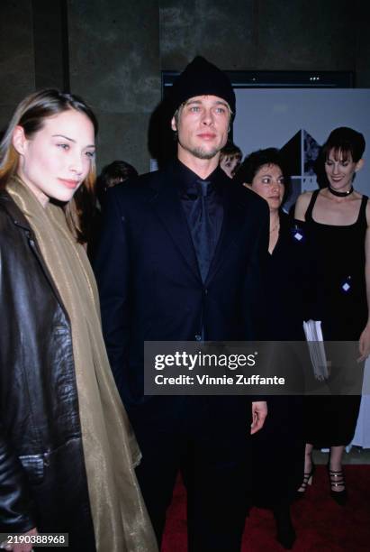 British actress Claire Forlani, wearing a leather coat with a long gold scarf, and American actor Brad Pitt, who wears a black suit with a black tie...