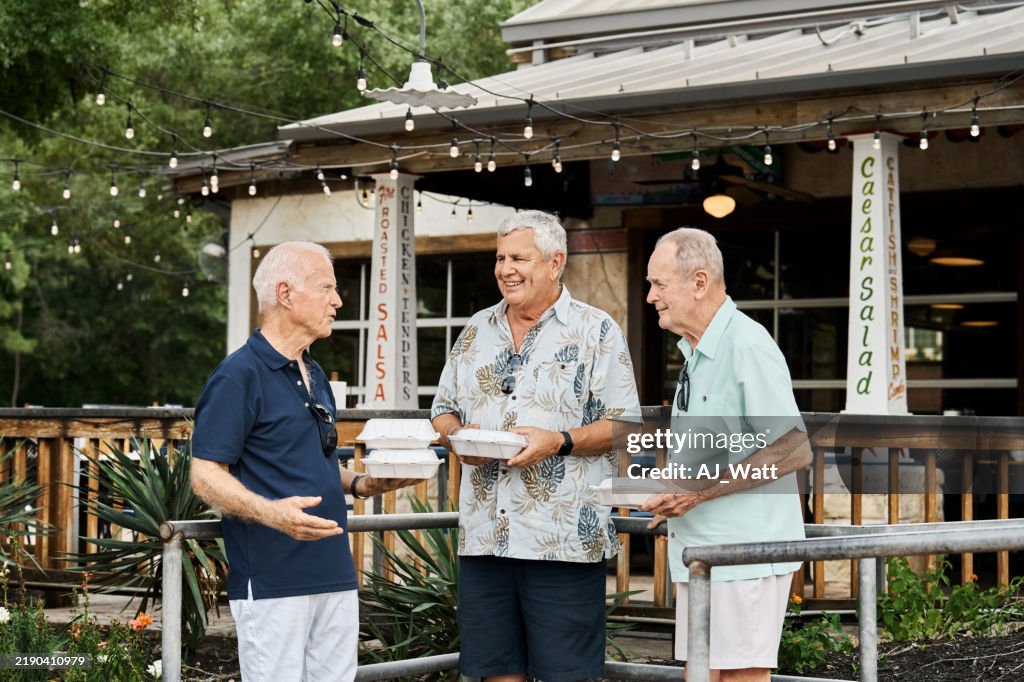 Group of Senior friends walking out with takeout containers