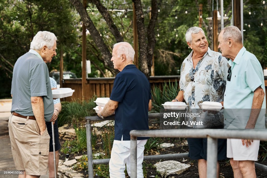 Senior male friends carrying takeout food leaving restaurant