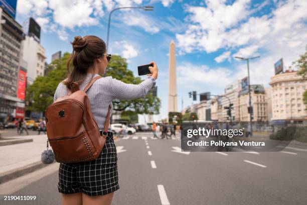 tourist macht ein foto am obelisken von buenos aires - obelisk von buenos aires stock-fotos und bilder