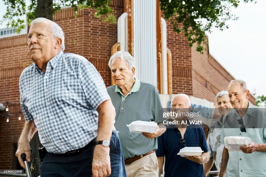 Group of senior friends walking out with takeout containers