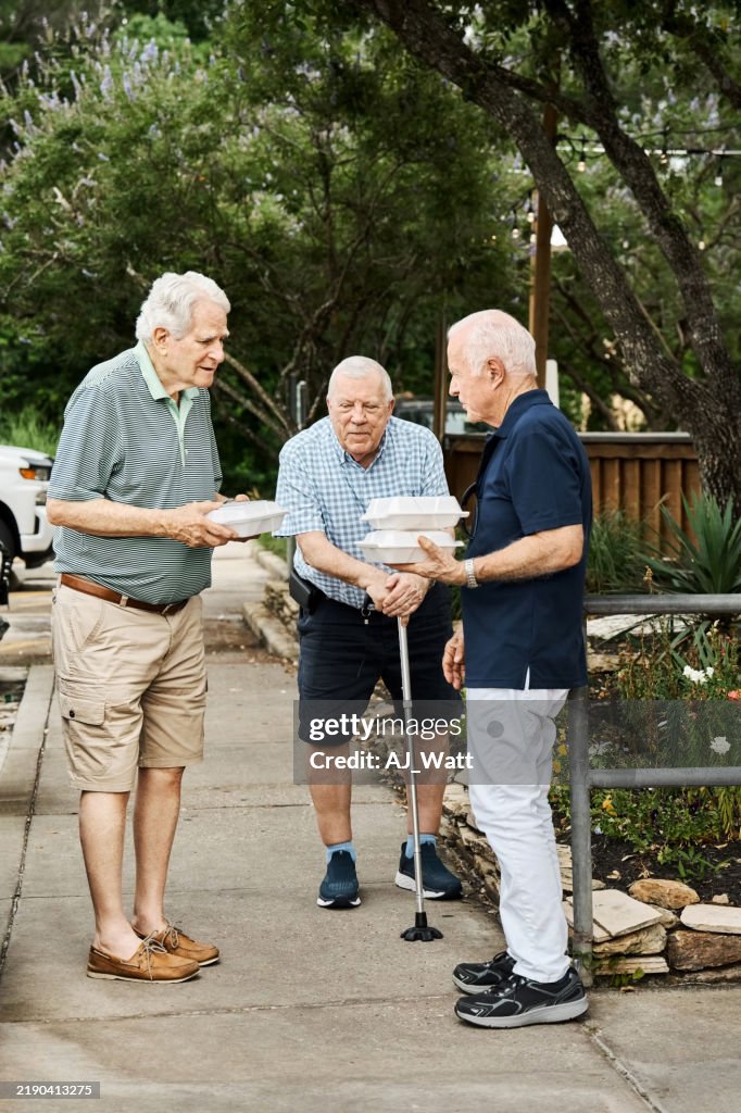 Senior friends with takeout containers standing outside and talking