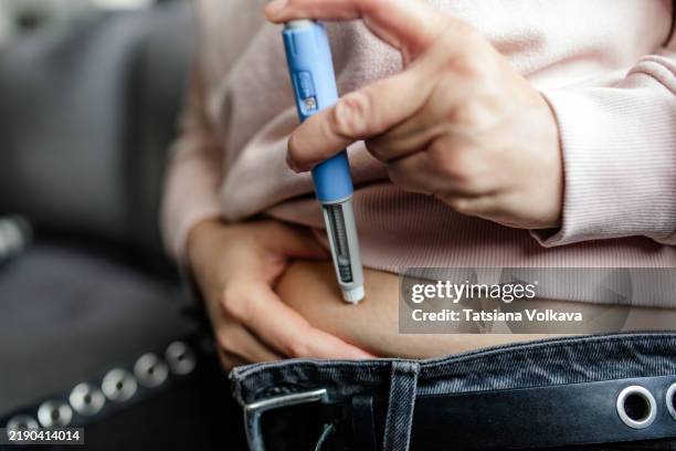 woman self-injecting semaglutide for weight loss therapy at home - seringa imagens e fotografias de stock