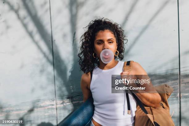 multiracial woman blowing bubble gum bubble in sun - bubble gum stock pictures, royalty-free photos & images