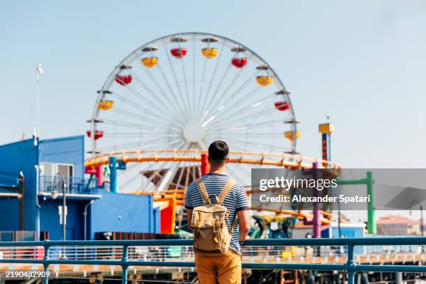 rear view of a man looking at colorful vibrant ferris wheel at santa monica pier, los angeles, usa - oeste dos estados unidos imagens e fotografias de stock
