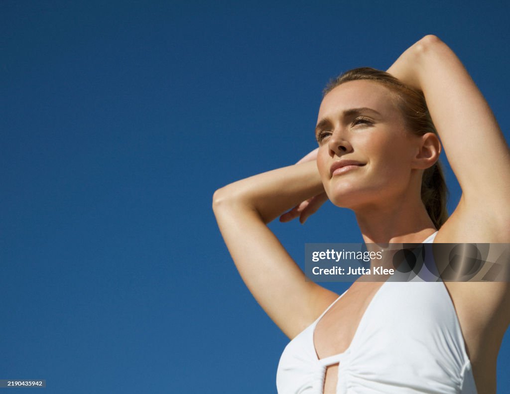 Portrait of a young woman with arms crossed over head