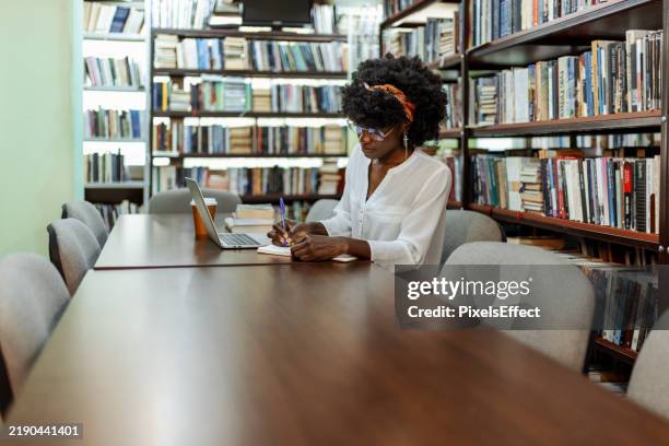 focused black female student studying in a library setting - public library stock pictures, royalty-free photos & images
