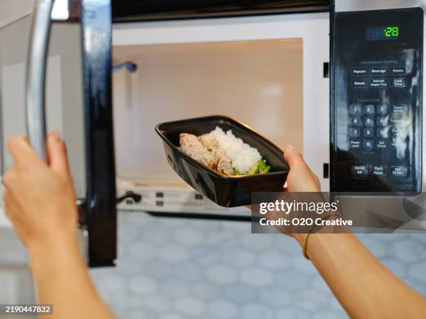 woman warming a ready-to-eat meal in a home kitchen - convenience food stock pictures, royalty-free photos & images