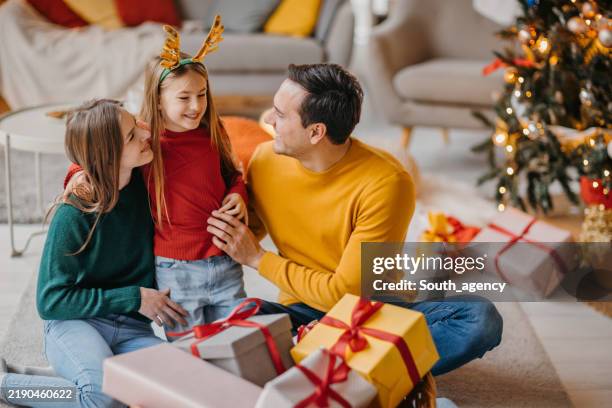 happy family celebrating christmas with gifts and enjoying festive moments together - antler stock pictures, royalty-free photos & images