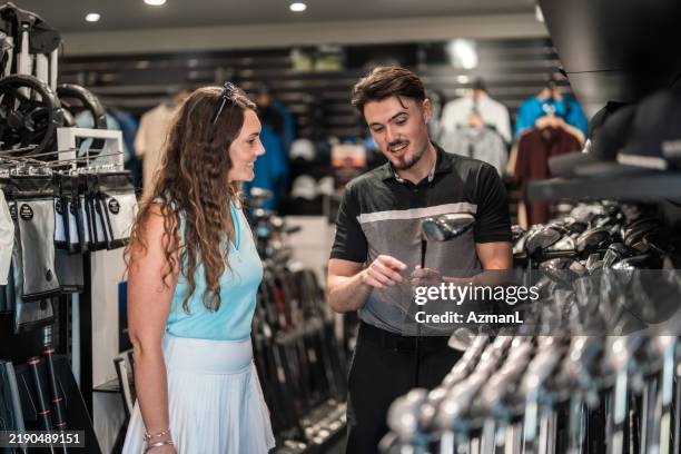enthusiastic caucasian female shopping for golf clubs with expert guidance - taco de golfe imagens e fotografias de stock
