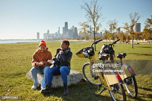 friends taking a break from bike riding to eat snack - chicago outfit imagens e fotografias de stock