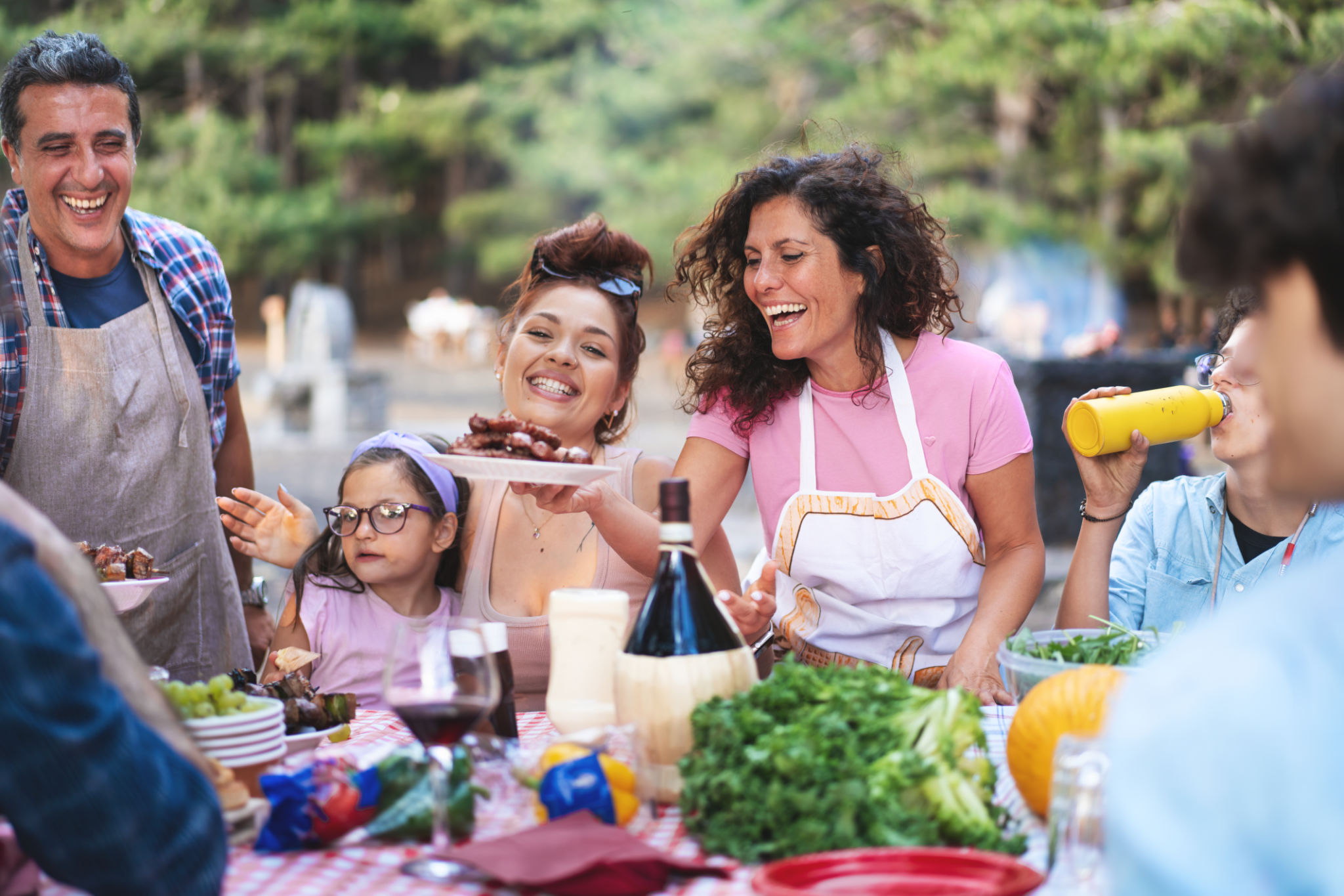 Joyful family barbecue, multigenerational outdoor dinner, diverse group laughing at summer picnic Joyful family barbecue, multigenerational outdoor dinner, diverse group laughing at summer picnic