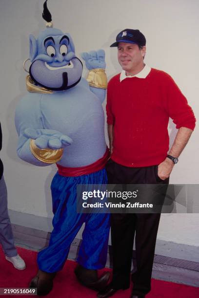 American media executive Michael Eisner, Walt Disney Company chief executive officer, wearing a red sweater over a white shirt with black trousers...
