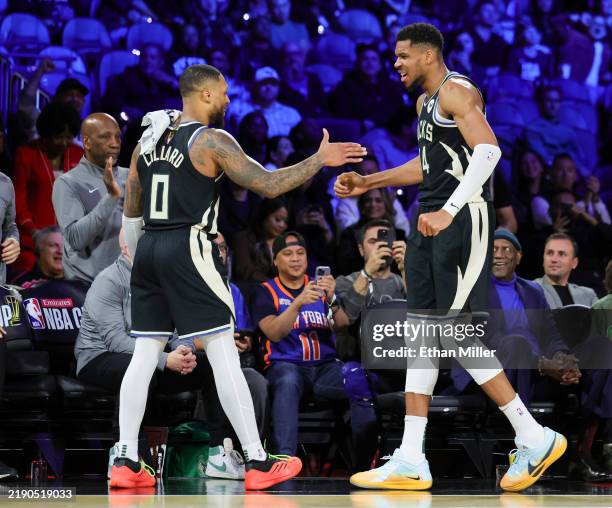 Damian Lillard and Giannis Antetokounmpo of the Milwaukee Bucks slap hands at the bench after Antetokounmpo checked out late in the fourth quarter of...