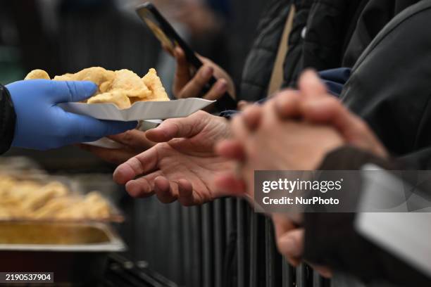 People receive traditional Christmas dishes during the 28th annual 'Christmas Eve - Christmas Food Handout,' a charity event organized and sponsored...