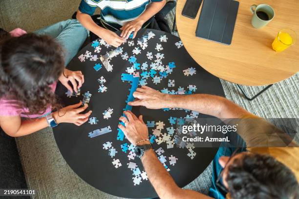 padre hispano se involucra con los niños resolviendo rompecabezas con alegría - familia con dos hijos fotografías e imágenes de stock