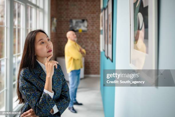 art enthusiasts observing exhibits in gallery interior with natural lighting. - espetáculo de arte imagens e fotografias de stock