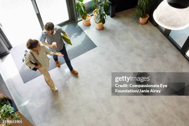 young man and woman walking in modern office lobby - man walking left to right stock pictures, royalty-free photos & images