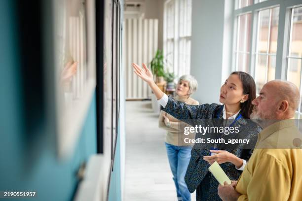 art gallery curator showing artwork to visitors during an engaging tour - espetáculo de arte imagens e fotografias de stock
