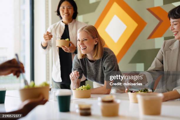 diverse group sharing a meal in a modern business environment - lunch break stock pictures, royalty-free photos & images