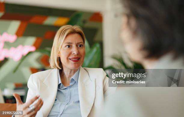 businesswoman engaged in discussion in a modern office setting - coach stock pictures, royalty-free photos & images