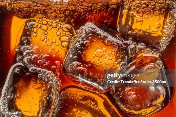 a close-up view of a cola with ice cubes submerged in it - cola stock pictures, royalty-free photos & images