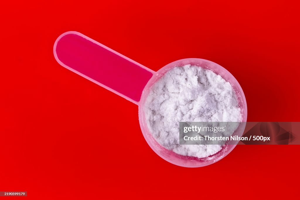 Scoop with whey protein for sporty lifestyle High angle view with red background