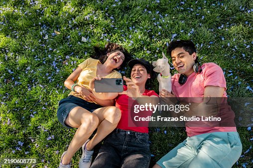 Friends taking a selfie or filming lying down on the public park Friends taking a selfie or filming lying down on the public park