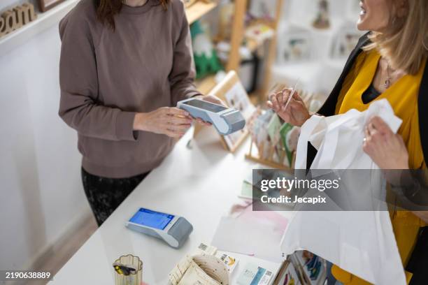 pagar con tarjeta de crédito en la tienda de regalos - tienda-de-regalos fotografías e imágenes de stock