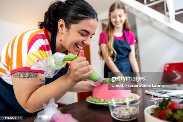 mid adult woman decorating a cake at home - decorar um bolo imagens e fotografias de stock