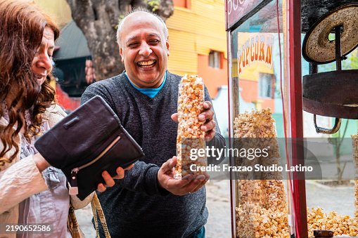 Tourist couple buying popcorn at a kiosk on a street Tourist couple buying popcorn at a kiosk on a street